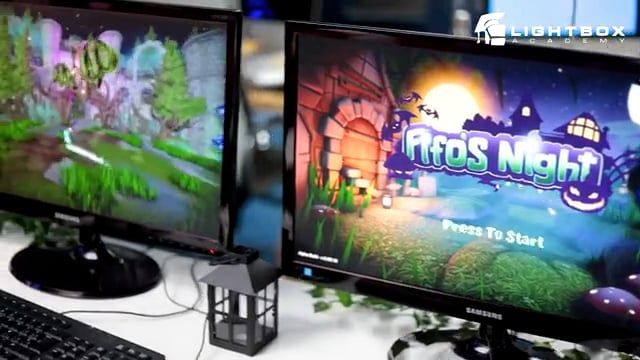 Dos monitores muestran, uno la pantalla de inicio y otro la jugabilidad de un videojuego colorido llamado “Fifo’s Night” en un aula de Lightbox Academy.