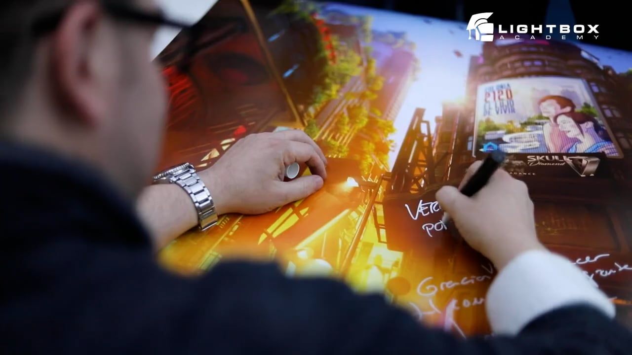 Primer plano de manos firmando un póster con ambiente futurista en tonos cálidos, donde aparece una ilustración de la ciudad y un cartel de “2120: Sé vivir”.