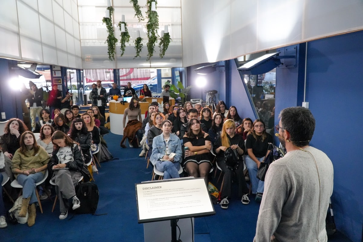 Josep Gatell dando una masterclass en un auditorio, frente a una audiencia numerosa con luces y equipo audiovisual.
